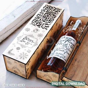 Peut inclure: Une boîte à vin en bois avec un motif découpé au laser et l'inscription "Happy New Year". À l'intérieur, une bouteille de vin repose sur de la paille. L'étiquette de la bouteille de vin indique "Organic Elderflower Presse". La boîte est en bois clair.