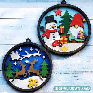May include: Two round, black-framed Christmas ornaments with festive scenes. One features a snowman, gnome, and gifts. The other depicts reindeer, a sleigh, and a bell. The backgrounds are blue with white accents.