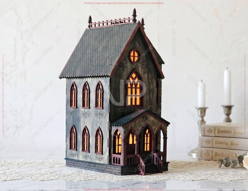 May include: A detailed, miniature haunted house model with a gray facade, dark roof, and arched windows. The windows glow with an orange light, suggesting an interior light source. The house has a porch and is set on a decorative surface.