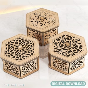 May include: Three hexagonal wooden boxes with intricate laser cut designs. The boxes are made of light brown wood and have a natural finish. Each box has a different design, featuring floral, geometric, and swirling patterns.