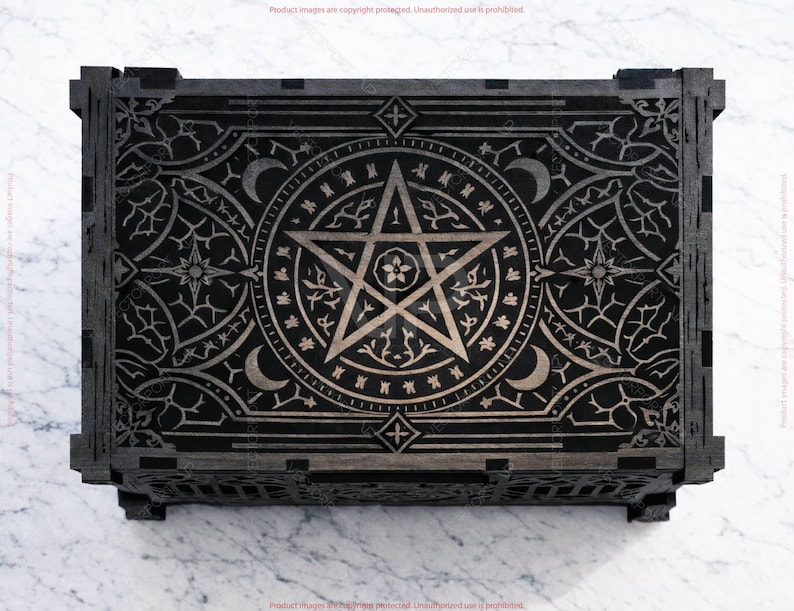 May include: A black wooden box with intricate silver-colored engravings. The design features a central pentagram, crescent moons, stars, and floral patterns. The box has a rectangular shape with detailed corner joints.