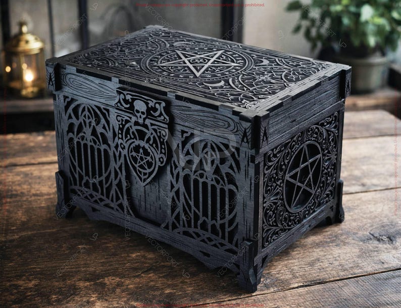 May include: Black wooden box with intricate gothic-style carvings. The box features a pentagram design on the lid and sides, along with skull and floral accents. The box is rectangular and sits on four small feet.