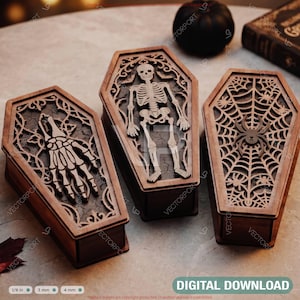 May include: Three wooden coffin-shaped boxes with intricate laser-cut lids. One lid features a skeletal hand, another a full skeleton, and the third a spider on a web. The boxes are dark brown with detailed cutouts, showcasing a layered design.
