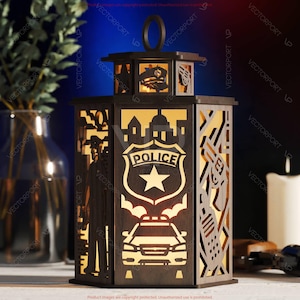 May include: A wooden lantern with a police theme. The lantern features cut-out designs of a police badge, a police car, a silhouette of a police officer, and city buildings. The lantern has a handle and is illuminated from within, creating a warm glow.