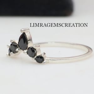 Könnte beinhalten: Ein silberner Ring mit einem Cluster aus schwarzen Edelsteinen. Die Edelsteine sind in einem kronenartigen Design angeordnet, mit einem birnenförmigen Stein in der Mitte. Der Ring ist vor einem weißen Hintergrund platziert, mit dem Text "LIMRAGEMSCREATION".