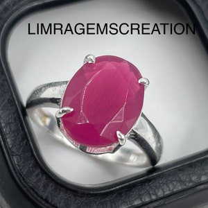 Könnte beinhalten: Ein silberner Ring mit einem großen, ovalen, rosafarbenen Edelstein. Der Ring ist in einer einfachen Fassung gefasst und der Edelstein ist facettiert.