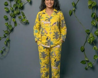 May include: Yellow pajama set with a tropical print featuring leopards, birds, and palm trees. The long-sleeved top and pants have white trim. The pajamas are made of a soft fabric.