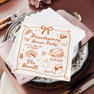 May include: White Friendsgiving dinner party napkins with an orange border and illustrations of food and drinks. The text reads "Friendsgiving Dinner Party" and "Let's eat, drink, and be thankful!" with the date 10.29.2025 and the name "The Bennett".