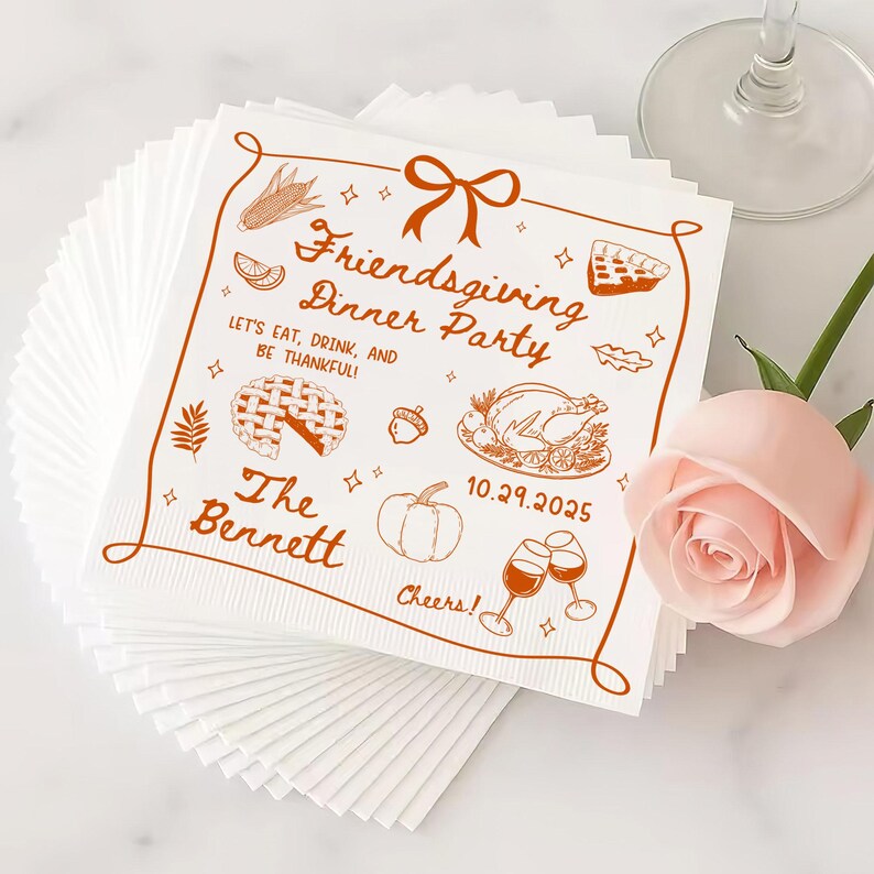 May include: White Friendsgiving dinner party napkins with brown illustrations of food and text. The text reads "Friendsgiving Dinner Party", "Let's Eat, Drink, and Be Thankful!", "The Bennett", and "10.29.2025". A stack of napkins is visible.