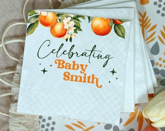Könnte beinhalten: Weiße Papierservietten mit einem Rautenmuster und dem Text "Celebrating Baby Smith". Die Servietten zeigen ein Design aus Orangen, grünen Blättern und weißen Blüten. Der Text ist in Grün und Orange gehalten.