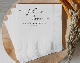 May include: White paper napkins with black calligraphy that reads "just love" with a small heart symbol. Below the text is "BRIAN & SOPHIA" and the date "06.22.2025".
