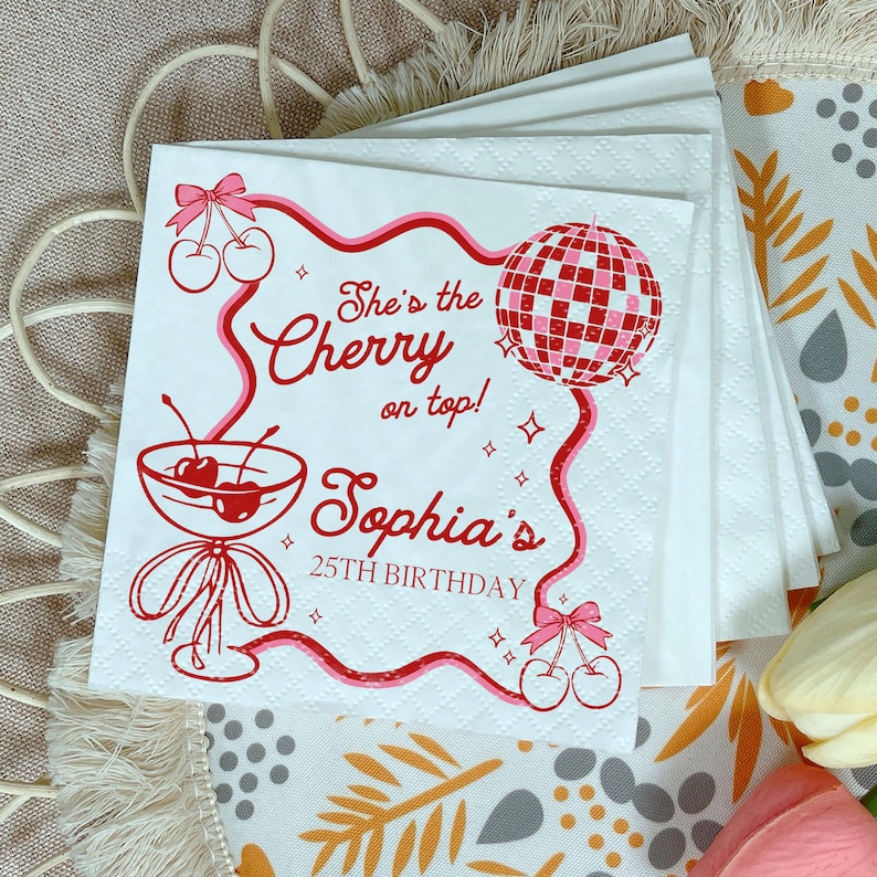 May include: White paper napkins with a red and pink cherry design. The napkins feature the text "She's the Cherry on top! Sophia's 25th Birthday" with a disco ball and cherry illustrations.