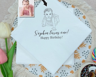 Könnte beinhalten: Weiße quadratische Servietten mit einer schwarzen Strichzeichnung eines Babys und dem Text "Sophia turns one! Happy Birthday!". Ein kleines Foto eines Babys in einem rosa Kleid befindet sich in der oberen linken Ecke. Die Servietten liegen auf einem dekorativen Platzset.