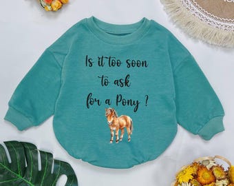 May include: A teal blue long-sleeved sweatshirt with the text "Is it too soon to ask for a pony?" and a cartoon image of a brown pony.