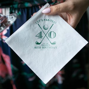 May include: White square paper napkin with a green golf-themed design. The text reads "LET'S PAR-TEE!" with crossed golf clubs, a golf ball, and the number "40". Below, it says "DAVID'S 40TH BIRTHDAY, DALLAS, TEXAS".