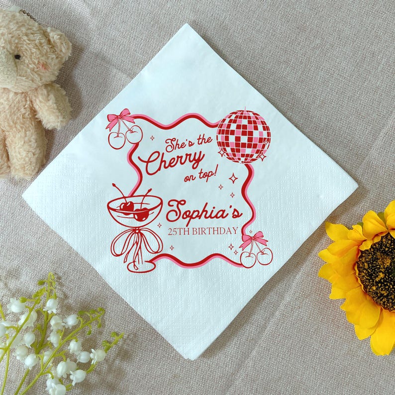 May include: White square paper napkin with a red and pink design. The design includes a cocktail glass with cherries, a disco ball, and text that reads "She's the Cherry on top! Sophia's 25th Birthday."