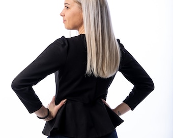 May include: A black peplum jacket with long sleeves. The jacket is paired with a dark blue denim skirt. The model has long blonde hair and is facing away from the camera, with hands on hips.