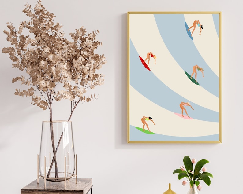 May include: A framed illustration of five women surfing on blue and white waves. The women are all wearing bikinis and are riding different colored surfboards.
