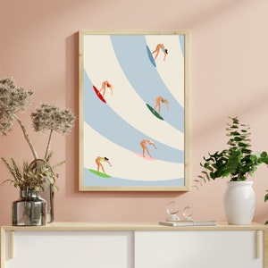 May include: A framed illustration of five women surfing on blue and white waves. The women are wearing bikinis and are in various poses on their surfboards.