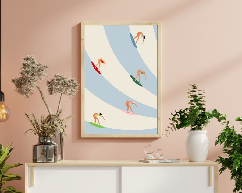May include: A framed illustration of five women surfing on blue and white waves. The women are wearing bikinis and are in various poses on their surfboards.