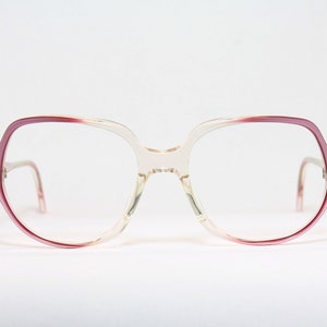May include: A pair of pink and clear plastic eyeglasses with a unique, geometric frame shape.
