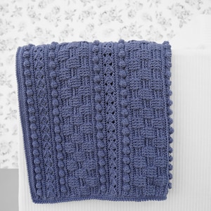 May include: A blue crocheted blanket with a textured pattern and a fringe border.