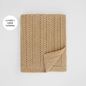 May include: A folded, beige crochet blanket with a textured stitch pattern. The blanket has a rectangular shape with a folded corner, revealing the detailed edge. The text "11 SIZES + VIDEO TUTORIAL" is in a white circle in the upper left corner.