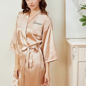 May include: A gold satin robe with a black embroidered name "Joanna" on the left side of the chest.