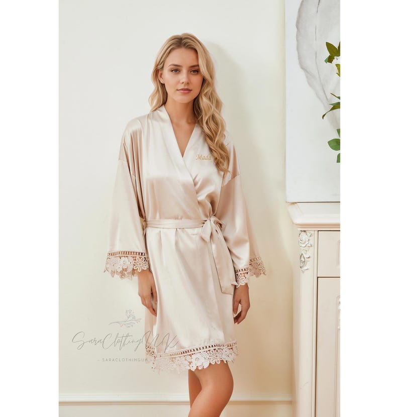May include: A champagne-colored satin robe with lace trim and a personalized embroidery that says "Maid".