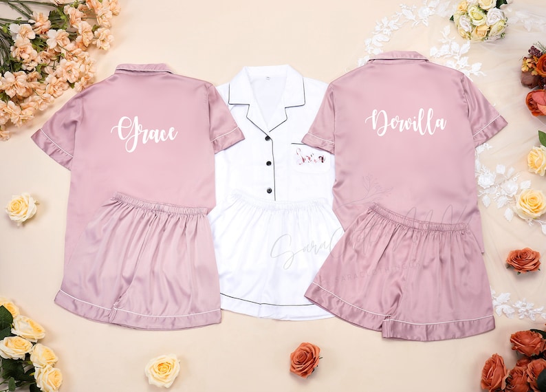 May include: Three sets of matching pajamas, one white and two pink. The pink pajamas have the names "Grace" and "Dorvilla" embroidered on the back of the shirts.