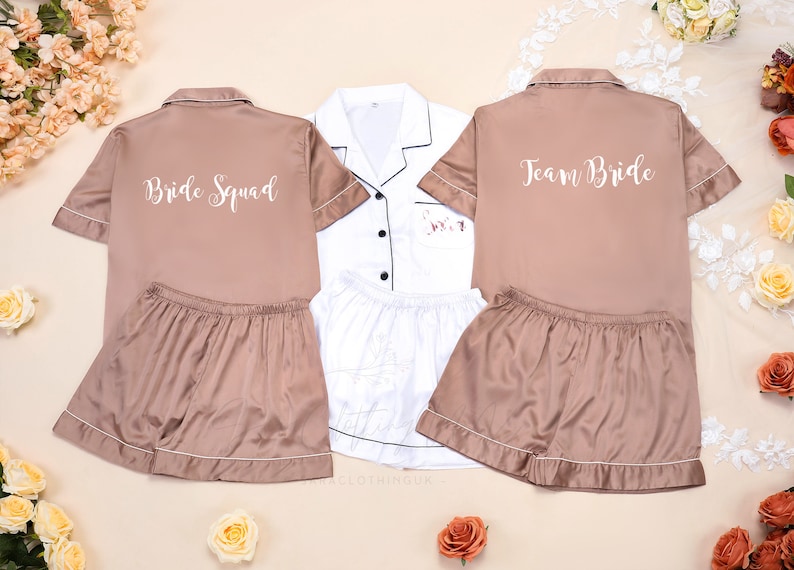 May include: Three matching pajama sets with short sleeves and shorts. One set is white with black trim and the other two are a light brown color. The brown sets have the text "Bride Squad" and "Team Bride" printed on the back.