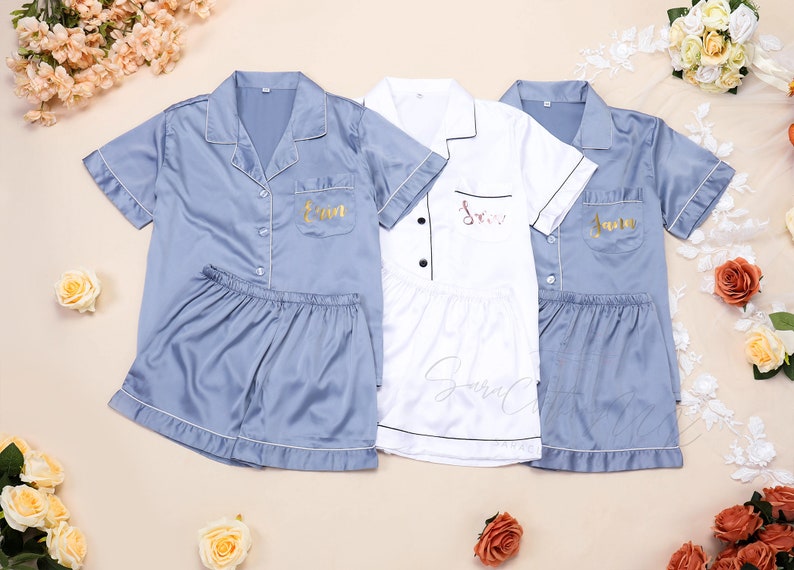 May include: Three matching pajama sets with short sleeves and shorts. The sets are in blue, white, and blue. Each set has a different name embroidered on the pocket: "Erin", "Jess", and "Jenna".