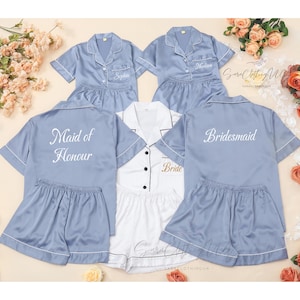 May include: Four blue satin pajama sets with short sleeves and shorts. The sets are embroidered with the words "Bride", "Maid of Honour", "Bridesmaid", and "Sister".