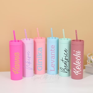 May include: Six personalized tumblers in various pastel colors, each with a matching straw. The tumblers are labeled with names in different fonts. Colors include pink, lavender, peach, light blue, mint green, and mauve. The tumblers are cylindrical and appear to be made of plastic.