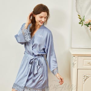 May include: A light blue satin robe with lace trim and a personalized embroidery that says "Esther".