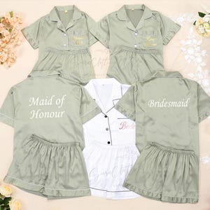 May include: Four sage green satin pyjama sets with short sleeves and shorts. The sets have white embroidery that says "Maid of Honour", "Bride", and "Bridesmaid".