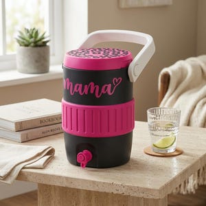 Könnte beinhalten: Ein schwarzer Getränkespender mit weißem Griff, einem pinken Deckel mit Leopardenmuster und einem pinken Silikonband. Das Wort mama ist in pinker Schreibschrift mit einem Herzsymbol auf der Vorderseite aufgedruckt. Ein pinker Zapfhahn ist unten.