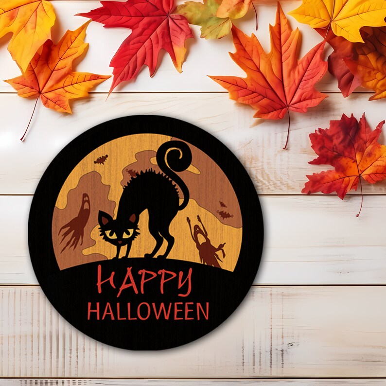 Op de afbeelding: Een ronde zwarte Halloween-decoratie met een zwarte kat, geesten en de tekst "Happy Halloween" in het rood. De achtergrond is lichtbruin met een maan en vleermuizen. Kleurrijke herfstbladeren omringen het beeld.