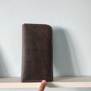 May include: A brown leather wallet with a stitched edge.