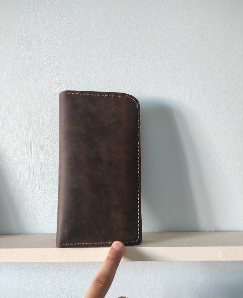 May include: A brown leather wallet with a stitched edge.