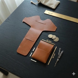 Könnte beinhalten: Ein braunes Lederportemonnaie und ein passender Kartenhalter sind auf einer schwarzen Oberfläche abgebildet. Der Kartenhalter ist 9,6 cm hoch und 6,1 cm breit. Ein Messinglineal, Münzen und ein kleiner Beutel sind ebenfalls vorhanden.