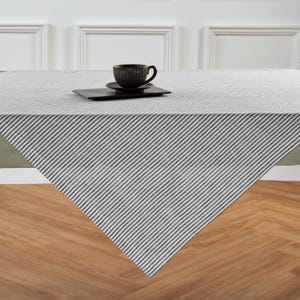 May include: A white tablecloth with thin black stripes. The tablecloth is laid out on a wooden table.