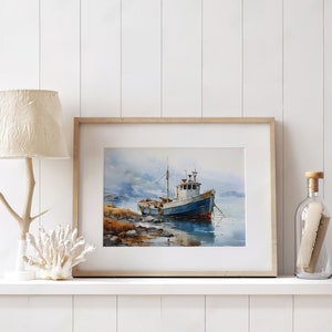 May include: A framed watercolour painting of a blue and white fishing boat moored in a harbour. The boat is surrounded by water and a rocky shore. The painting is set against a backdrop of a cloudy sky.