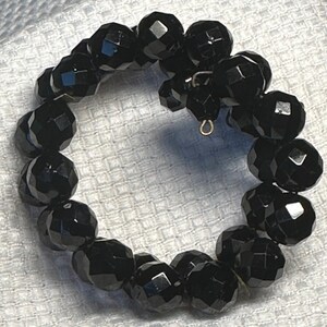 Puede incluir: Un brazalete negro de cuentas con un diseño facetado. El brazalete está hecho de cuentas redondas y tiene un cierre simple.
