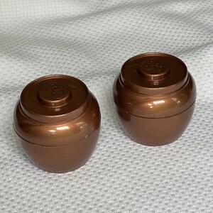 May include: Two brown ceramic salt and pepper shakers in the shape of small barrels. The shakers have a shiny, metallic finish.