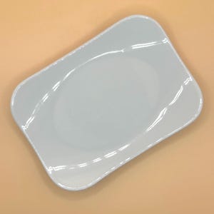 Puede incluir: Una fuente rectangular azul claro con bordes suavemente curvados. La fuente tiene una superficie lisa y brillante y un borde ligeramente elevado. La forma general es un rectángulo suavizado, adecuado para servir aperitivos o porciones pequeñas.