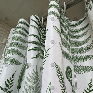 May include: White shower curtain with a green fern pattern. The curtain is hung on a silver shower rod.