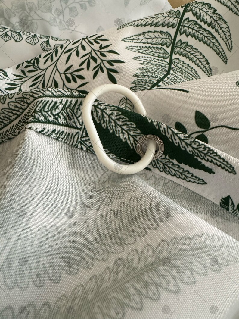 May include: White shower curtain with a green fern pattern. The curtain has a white plastic hook attached to it.