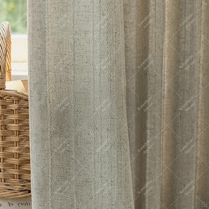 May include: Close-up of textured, light beige linen curtains with vertical stripes. A woven basket is partially visible on the left. The curtains are likely for a window, offering a neutral, natural aesthetic.