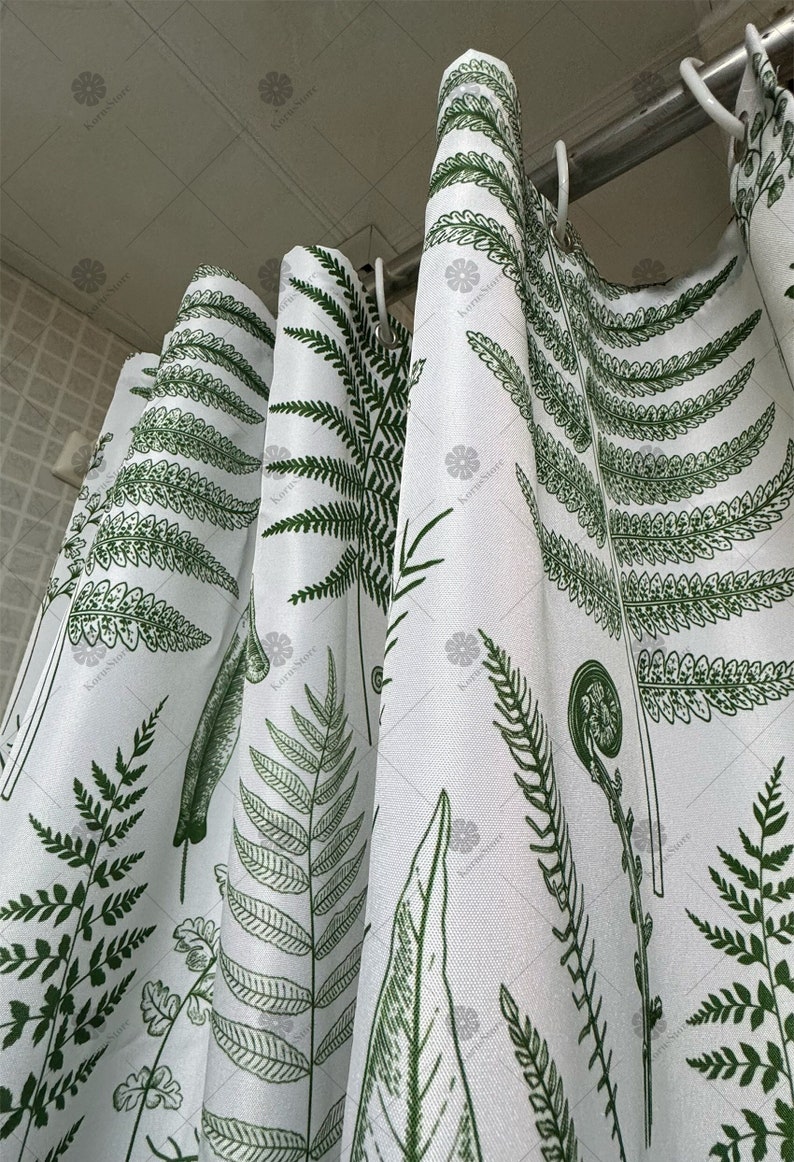 May include: White shower curtain with a green fern pattern. The curtain is hung on a silver shower rod.
